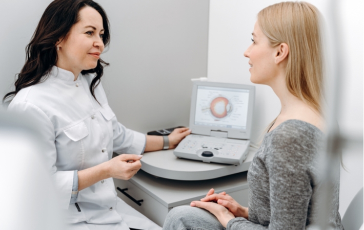 A woman seated next to her female optometrist as they discuss the condition of the woman eye's after her eye exam