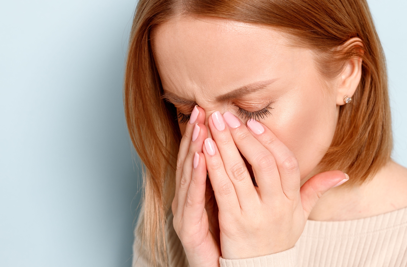 A woman holding her eyes in discomfort due to pain when she blinks