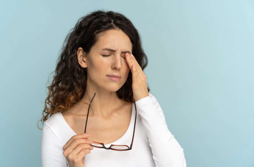 A woman taking off her glasses touching her eye's that feel tired