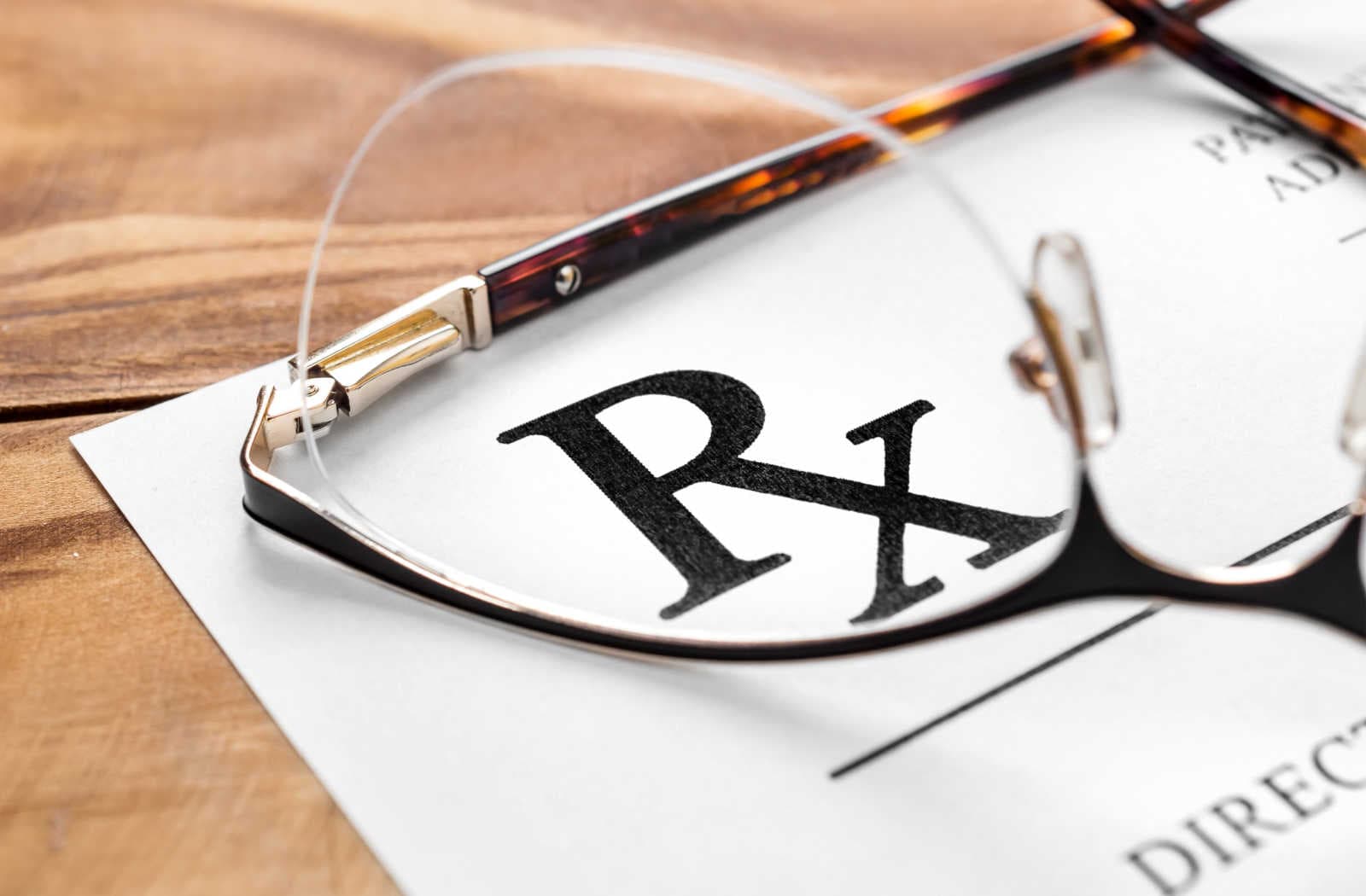 A close up of eyeglasses sitting on top of an eyeglass prescription paper