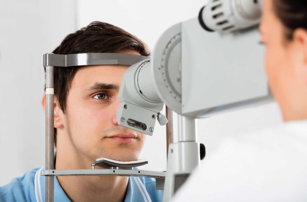 A man sitting in an optometrist's office looking into a machine that tests his vision.