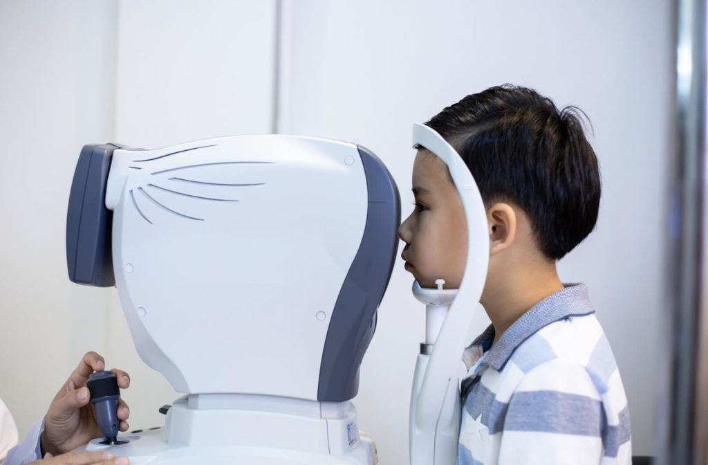 A young boy is looking through the Autorefractor screen while undergoing an eye examination at a clinic under the care of an optometrist.