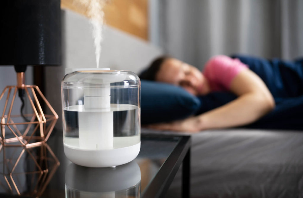 A close-up view of a humidifier in operation within a bedroom increases the moisture in the air as the individual sleeps.