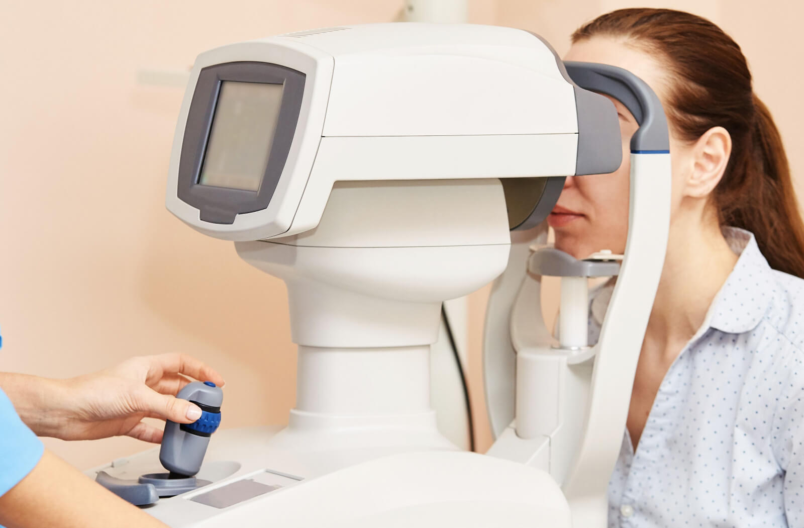 An optometrist preparing an OCT scan machine while a patient waits during their eye exam.
