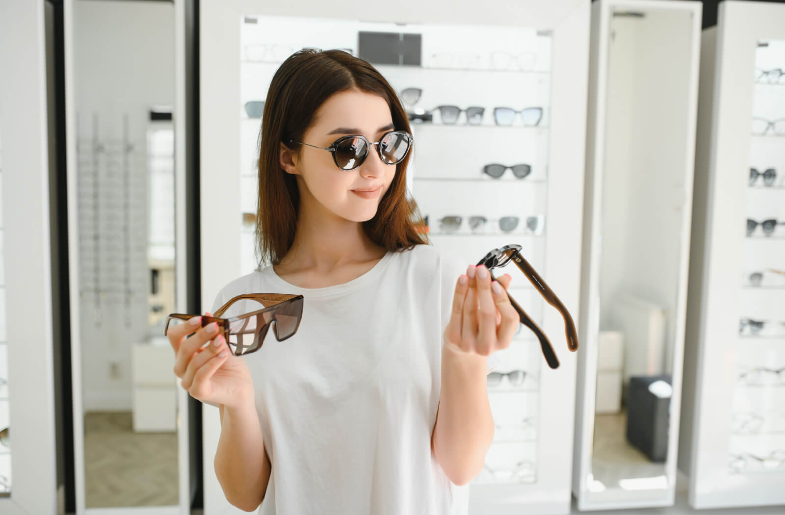 A patient trying on a pair of sunglasses, smiling while trying to choose between polarized and non-polarized lenses.
