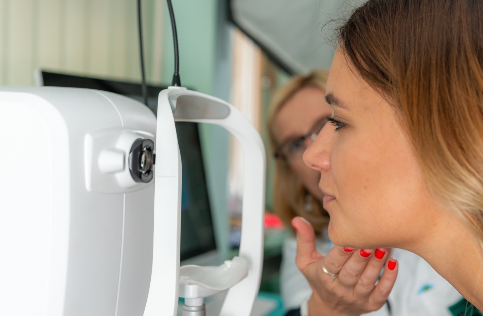 An optometrist adjusting a patient's chin during an OCT scan for an eye exam.