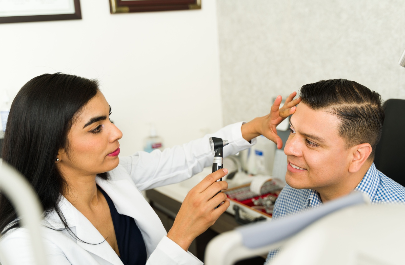 Optometrist examines patient’s eyes with a handheld scope during a routine vision assessment in a clinical setting