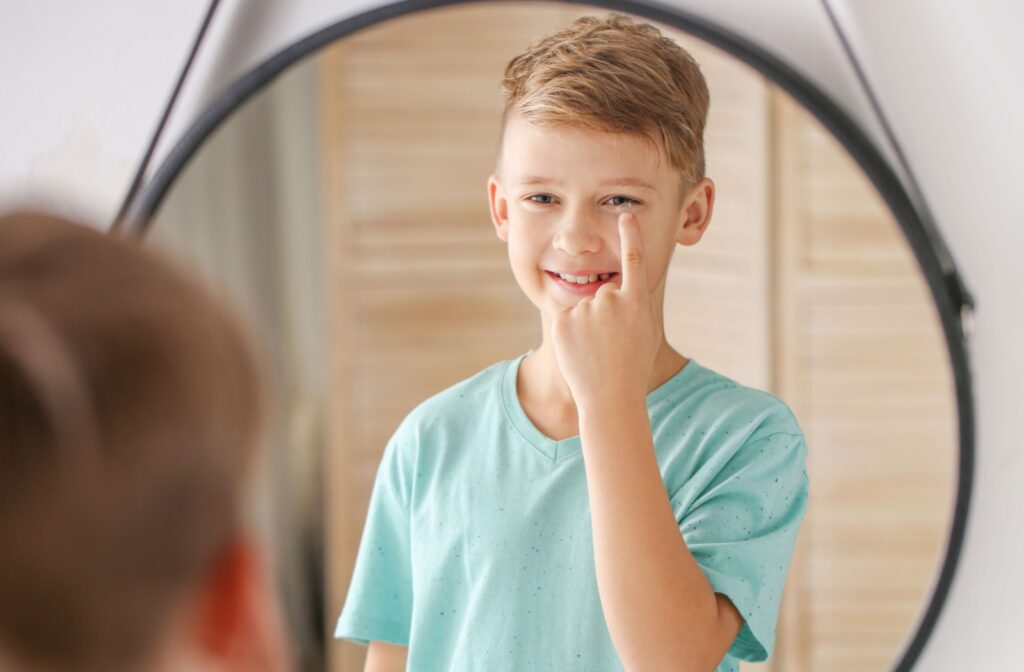 Young happy boy putting in contact lenses.