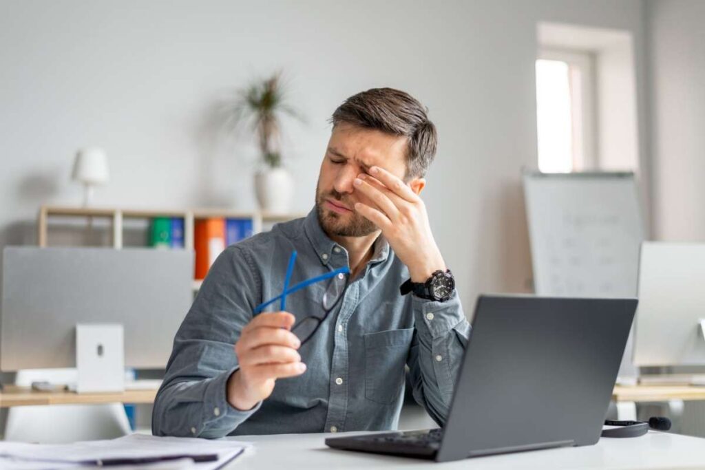 A person experiencing eye discomfort, which is a common symptom of dry eye and meibomian gland dysfunction—especially during long hours of screen use.